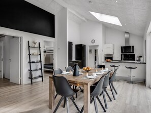 Un espace de vie moderne à aire ouverte comprenant un coin repas, une cuisine et une chambre en mezzanine.
