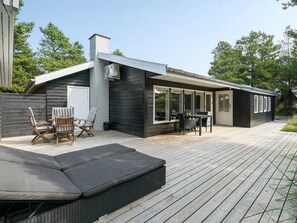 Una casa moderna con patio, posti a sedere all'aperto e un'ampia zona finestrata.