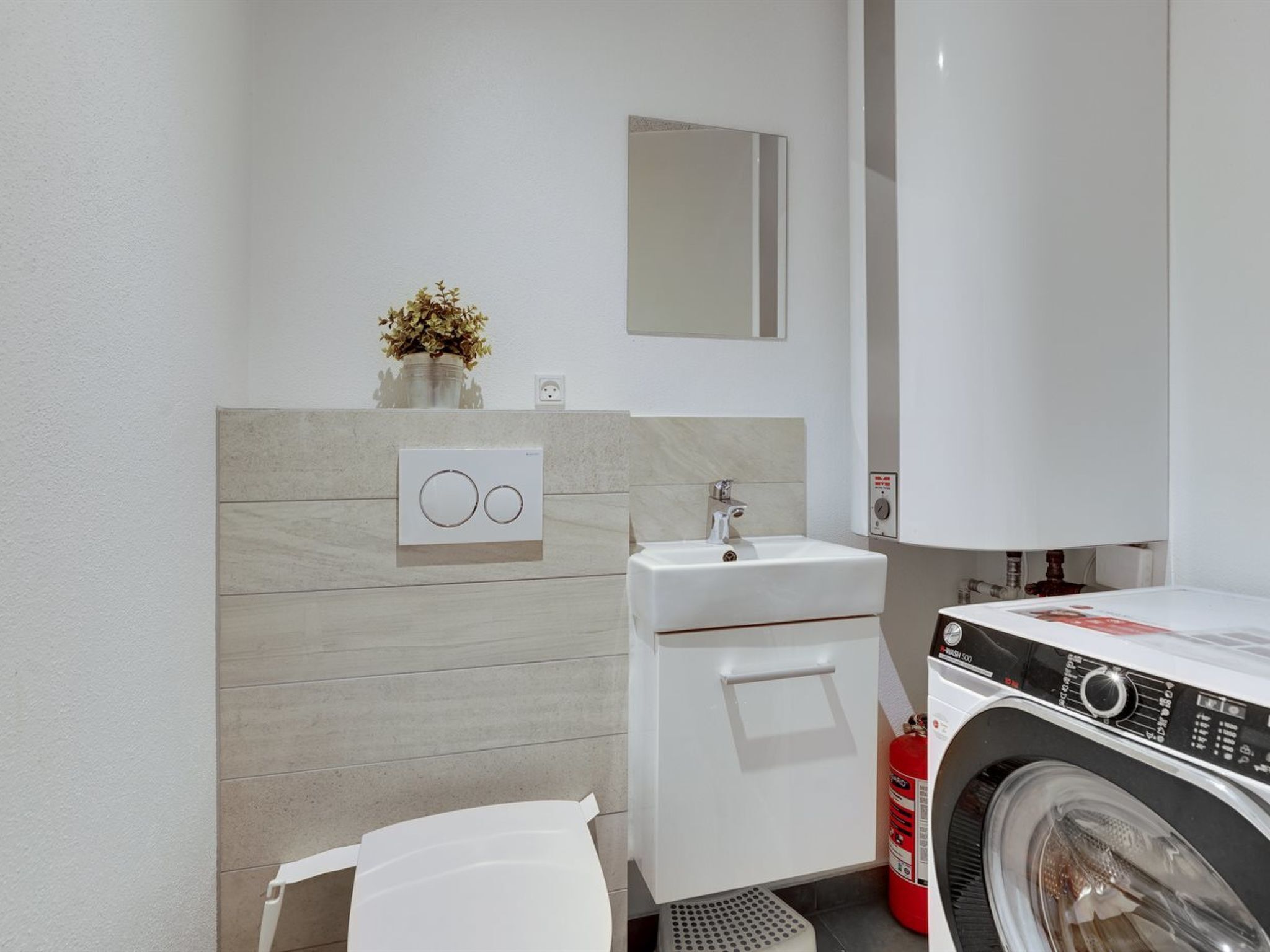 Une petite salle de bain comprenant un lavabo, un miroir et un lave-linge.