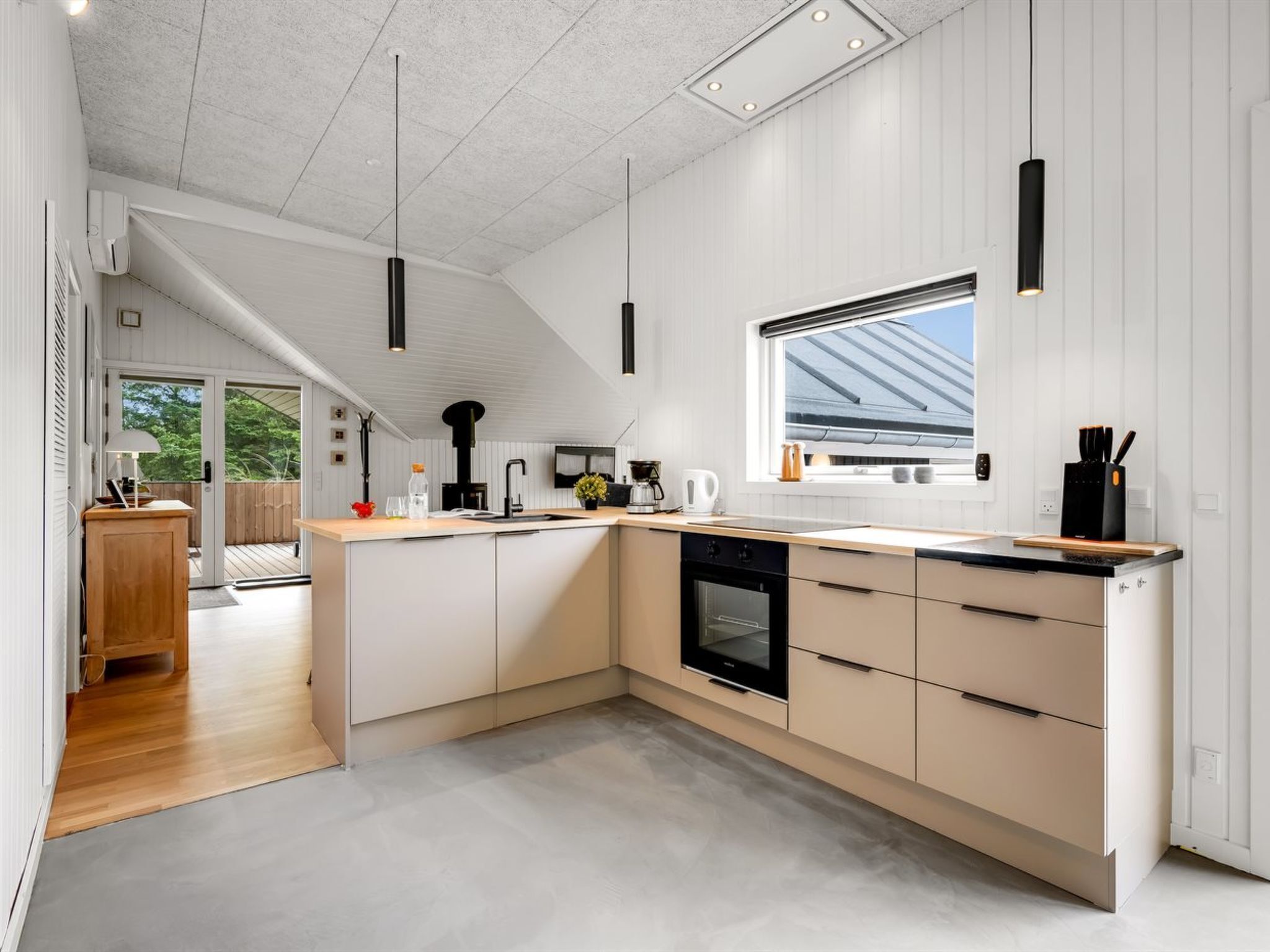 A modern kitchen with a large island, built-in oven, and a window with a view of the roof.