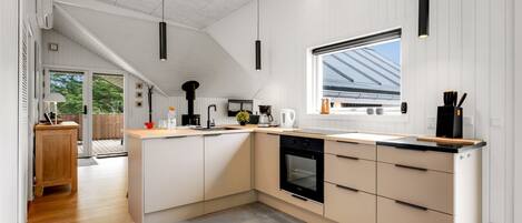 A modern kitchen with a large island, built-in oven, and a window with a view of the roof.
