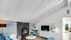 Ein modernes Wohnzimmer mit Kamin, blauen Sofas, einem Fernseher und einem weißen Schrank.
