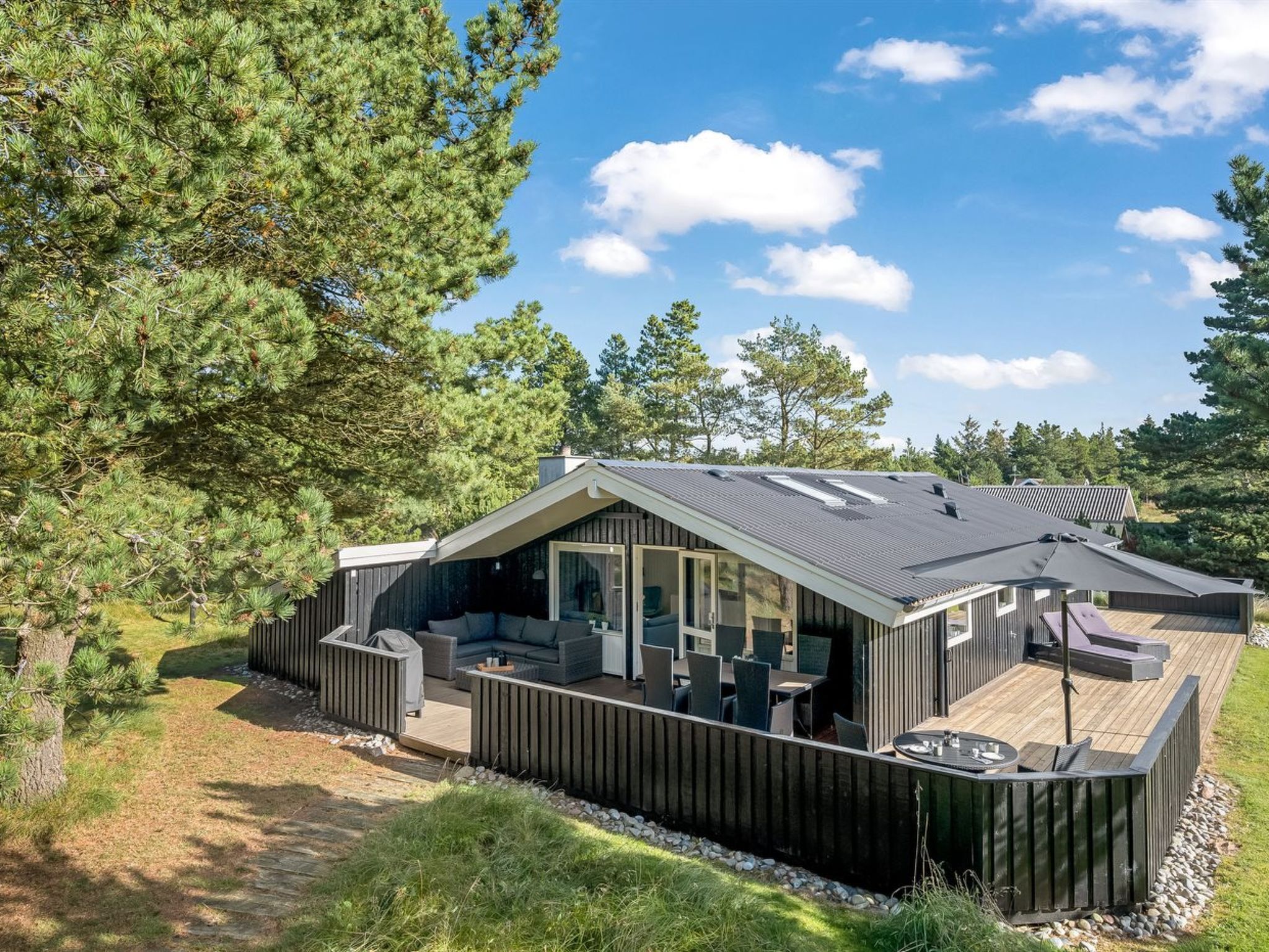 Een moderne blokhut met terras, grote ramen en een schuin dak.