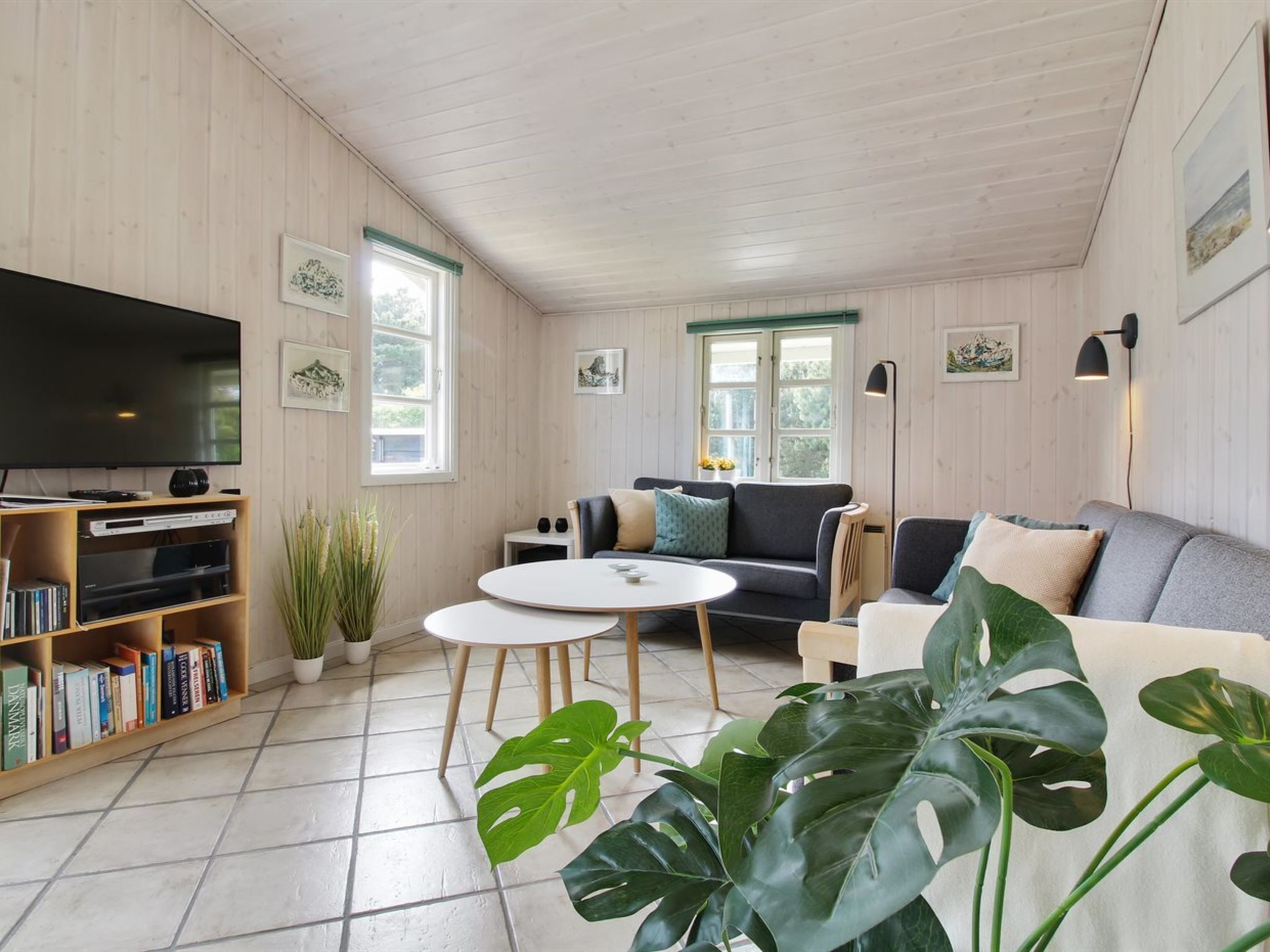 A modern living room with a flat-screen TV, a sofa, a coffee table, and a bookshelf.