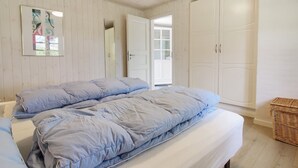 A bedroom with a large bed, a wardrobe, and a door leading to another room.