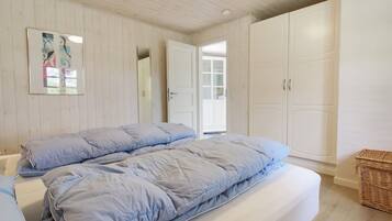 A bedroom with a large bed, a wardrobe, and a door leading to another room.