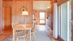 A wooden interior with a dining area featuring a round table and chairs, a clock on the wall, and a door leading to another room. - "Neja" - 400m from the sea by Interhome (Blåvand)