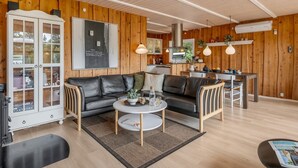 A modern living room with a sofa, coffee table, and a kitchen in the background.