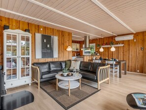 Una sala de estar moderna con un sofá, una mesa de centro y una cocina al fondo.