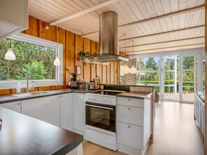 Una cocina moderna con paredes de madera, un ventanal y vistas al verdor.