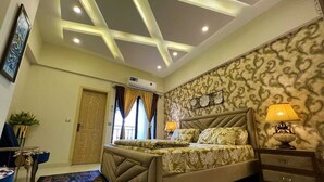 Un dormitorio con cama, mesitas de noche, un reloj de pared y un papel tapiz estampado.