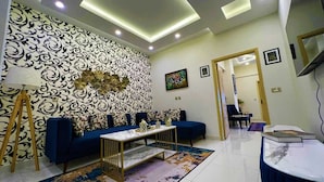 Una sala de estar moderna con un sofá azul, una mesa de centro blanca y un papel tapiz estampado.