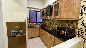 Una cocina funcional con armarios de madera, microondas, estufa y refrigerador.
