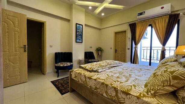 Un dormitorio con una cama grande, una silla, una puerta y una ventana.