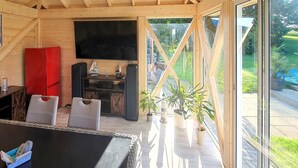 A cozy cabin with a wooden interior, a flat-screen TV mounted on the wall, and a dining area with a table and chairs. - Ferienwohnung Neppermin/Usedom (Neppermin/Usedom)