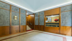 Un hall d’entrée spacieux avec un escalier en bois, une moquette rouge et un meuble à vin fixé au mur.