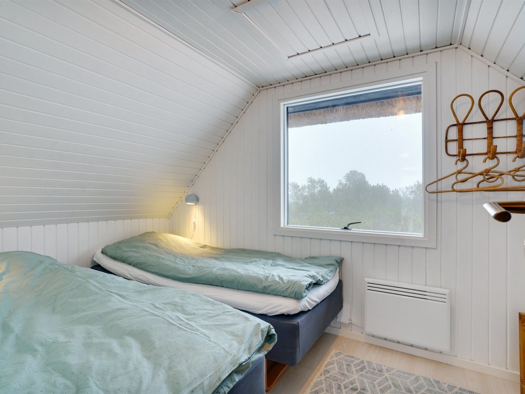 Une chambre avec deux lits, une fenêtre, un radiateur et un porte-vêtements.