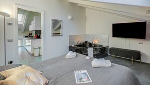 Une chambre d’hôtel moderne dotée d’un grand lit, d’une télévision à écran plat, d’un jacuzzi et d’une fenêtre de toit.
