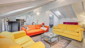 Un espace de vie de style loft avec un plafond haut, une table basse en verre et deux canapés aux couleurs vives.