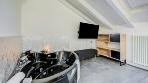 Une salle de bain moderne avec une baignoire sur pieds, un téléviseur à écran plat fixé au mur et une étagère intégrée en bois.