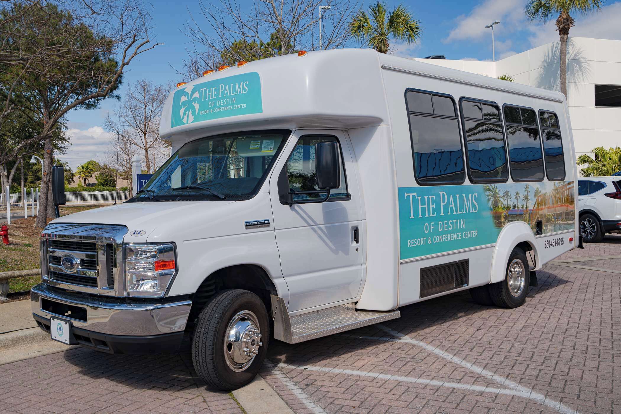 A white bus with "The Palms of Destiny Resort & Conference Center" branding parked on a paved area.