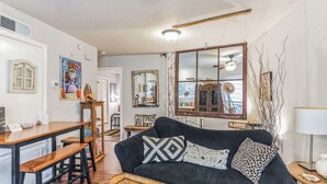 A living room with a black sofa, wooden coffee table, and a mirror. - Cozy Retreat in Central East Austin (Austin)