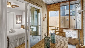 A room with a bed, a table with two patterned vases, a ceiling fan, and a view of the outside. - Cozy Retreat in Central East Austin (Austin)