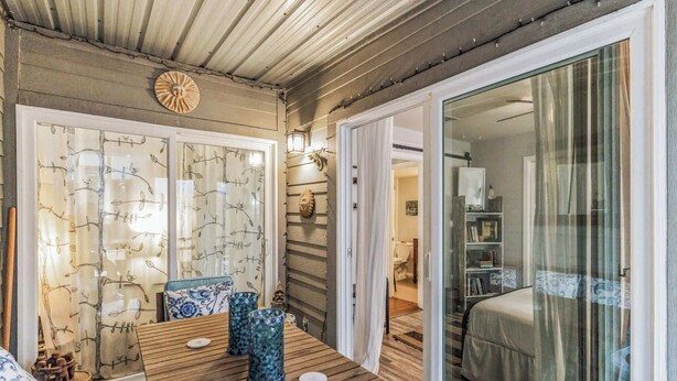 A room with a wooden table, chairs, a bed, and a glass door leading to another room. - Cozy Retreat in Central East Austin (Austin)