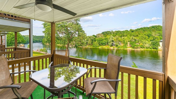 Ein überdachter Außenbereich mit Tisch und Stühlen mit Blick auf einen Fluss und bewaldete Hügel.