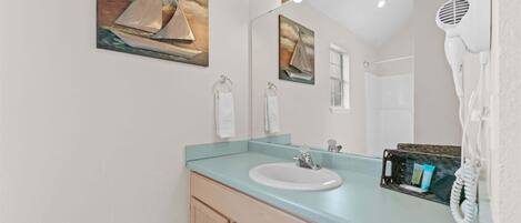 A bathroom with a sink, mirror, towel rack, and a hairdryer.