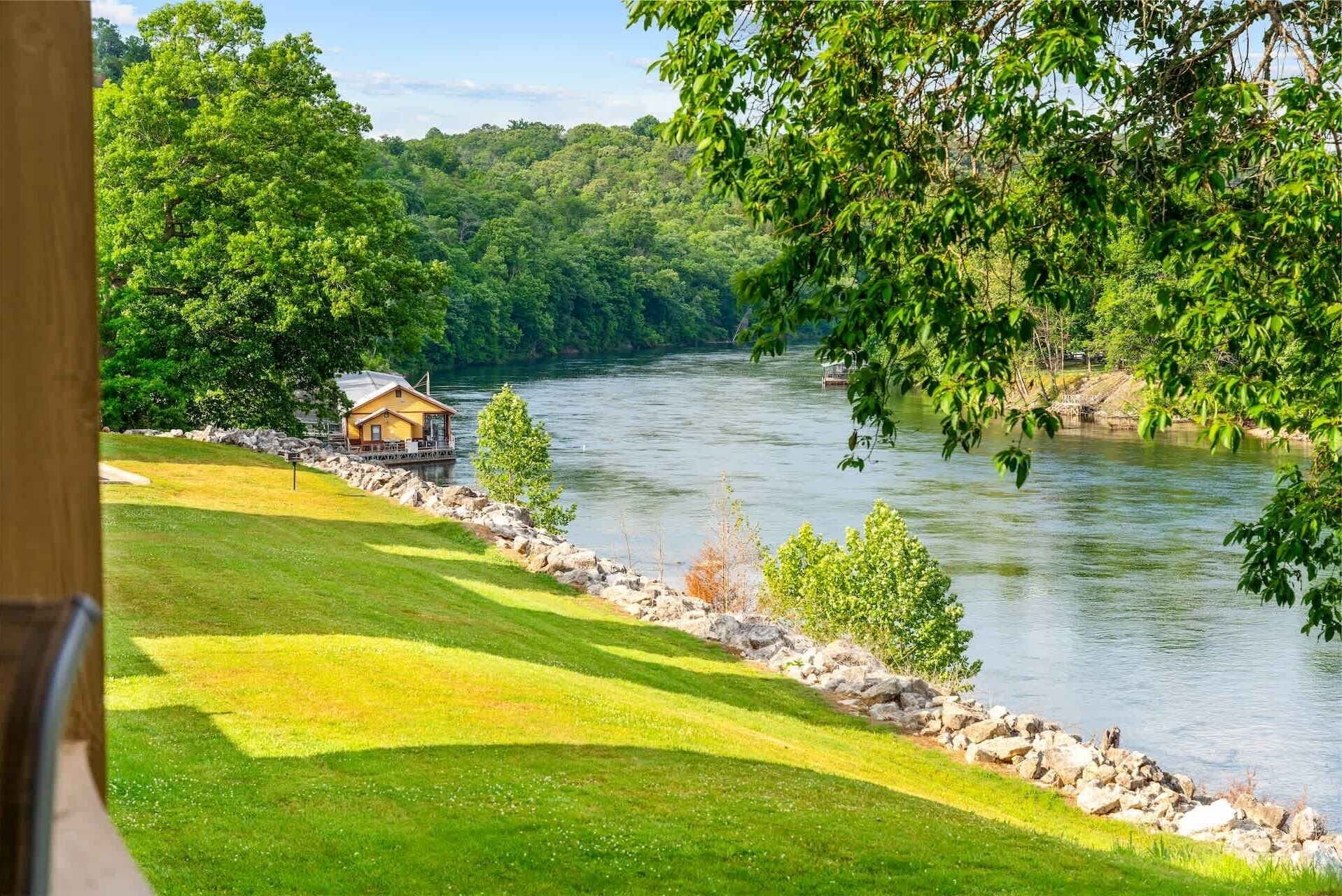 A riverside view with a cabin and a grassy area.