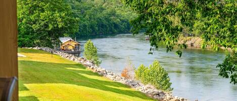 A riverside view with a cabin and a grassy area.