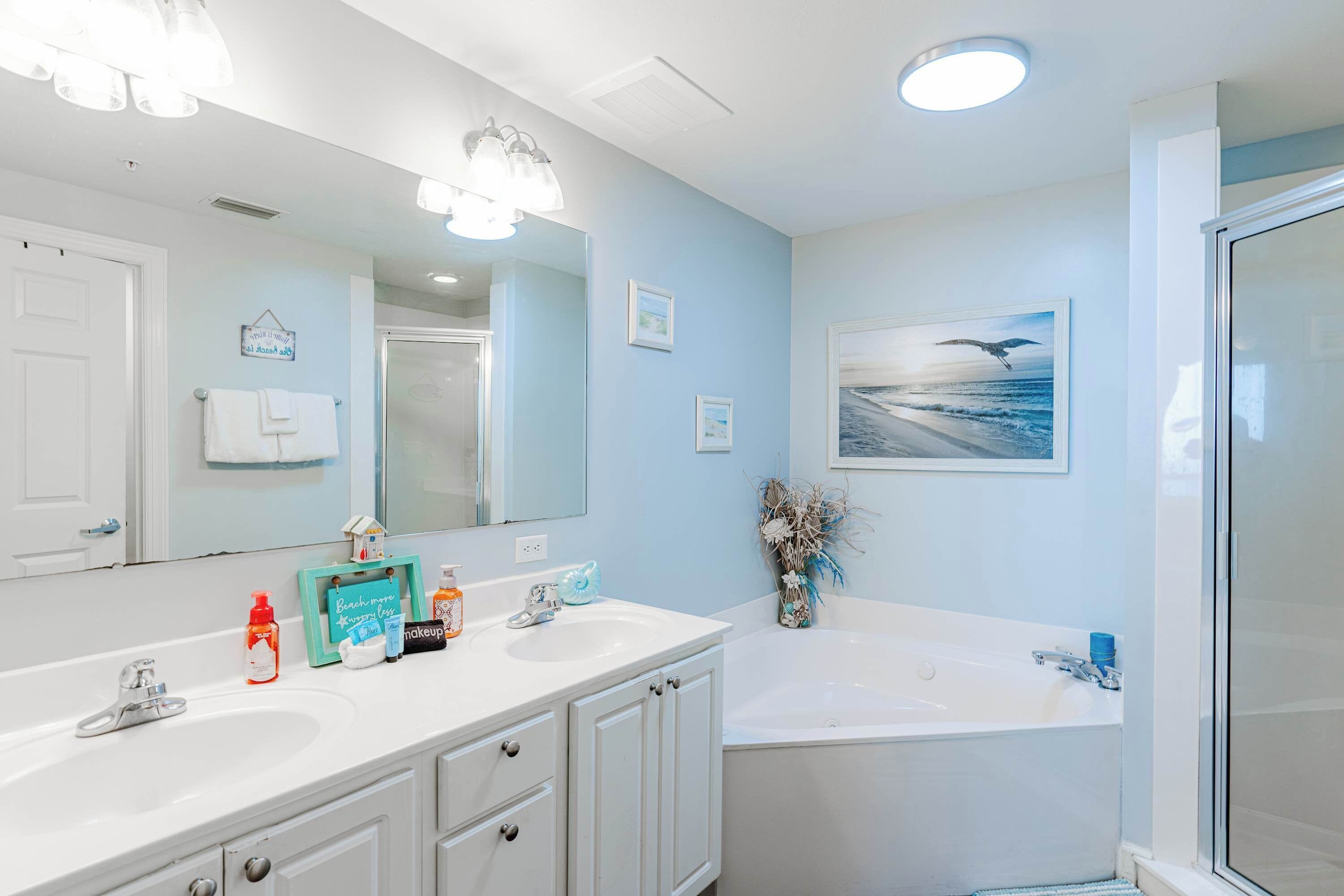 A bathroom with two sinks, a large mirror, and a shower.