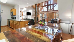 A spacious kitchen with wooden cabinets, a large island, and a stone accent wall. - Kemper's Duet Cabins (Branson)