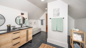Ein modernes Badezimmer mit einem Holzkosmetikschrank, zwei Waschbecken, einem großen Spiegel und einem Handtuchhalter.