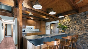 Una cocina con armarios de madera, pared de piedra y una barra con taburetes.