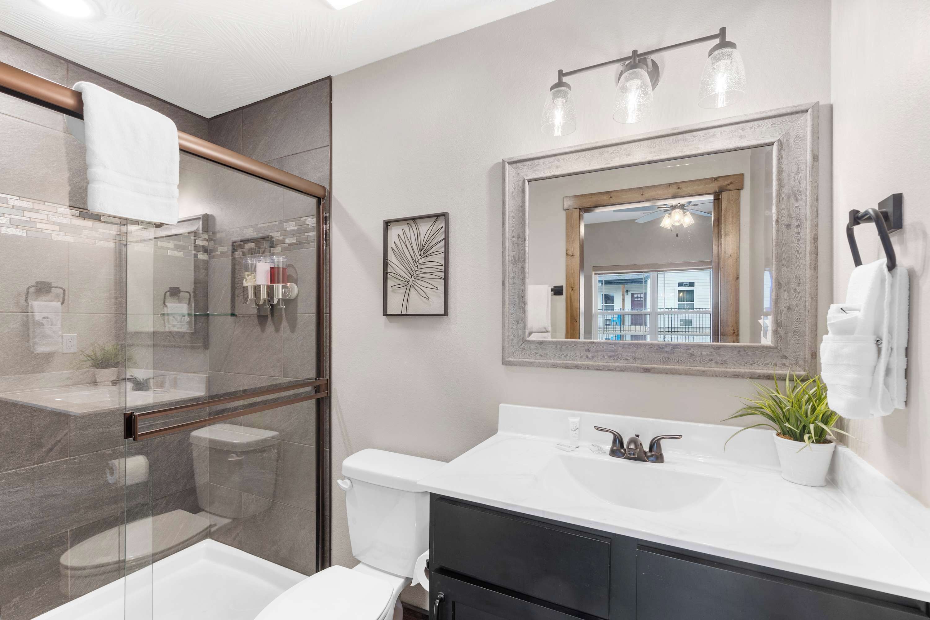 A modern bathroom with a glass shower enclosure, a white sink, and a large mirror.