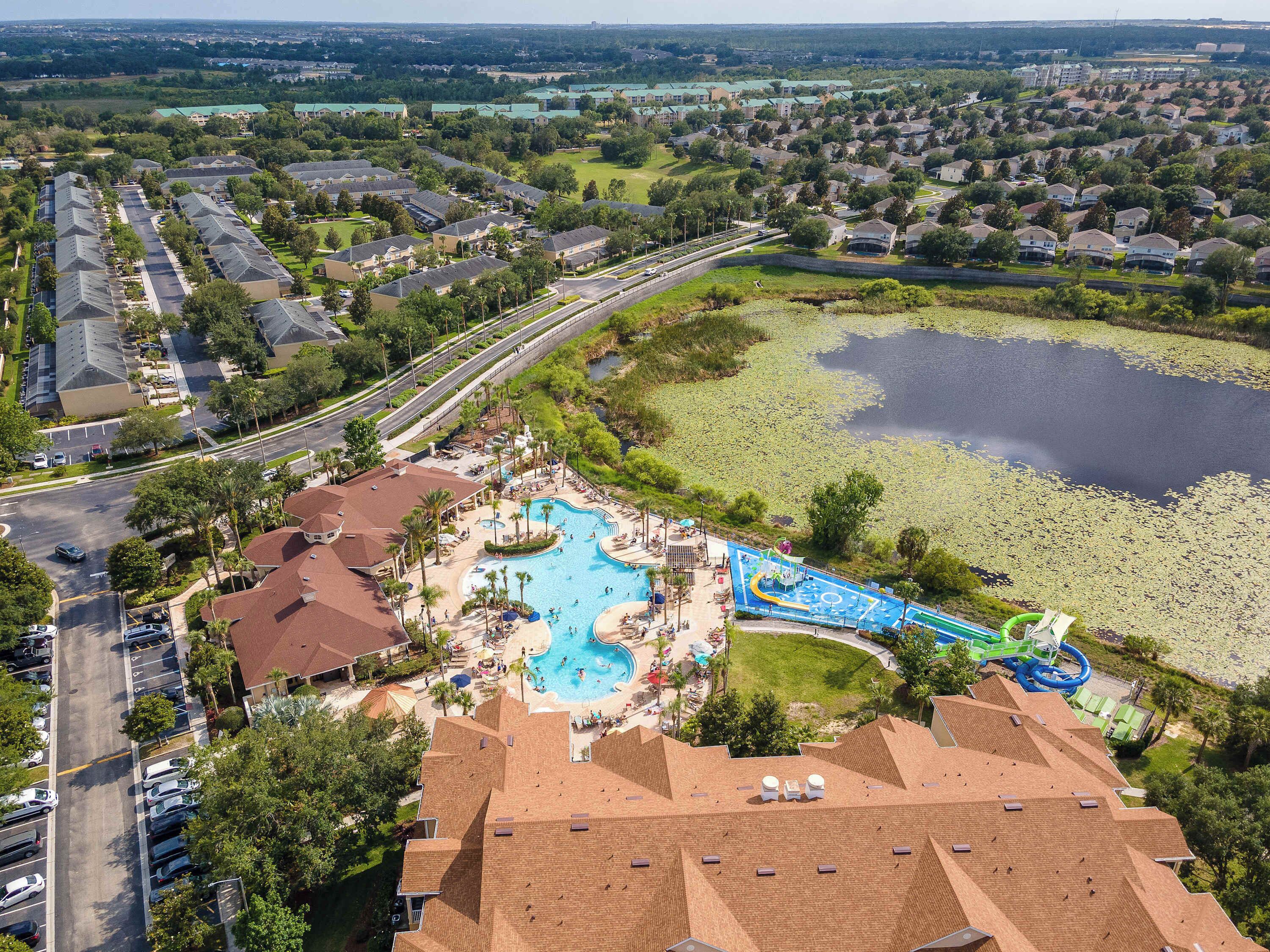An aerial view of a resort with a swimming pool, water park, and a large lake.