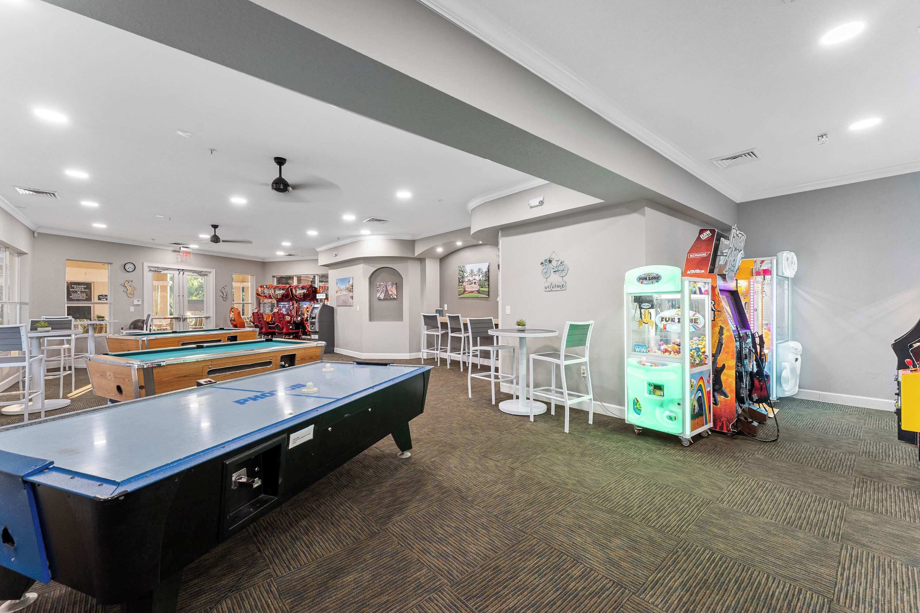 Une table de billard, une table de ping-pong et un distributeur automatique dans une pièce où se trouvent des chaises blanches et un sol recouvert de moquette.