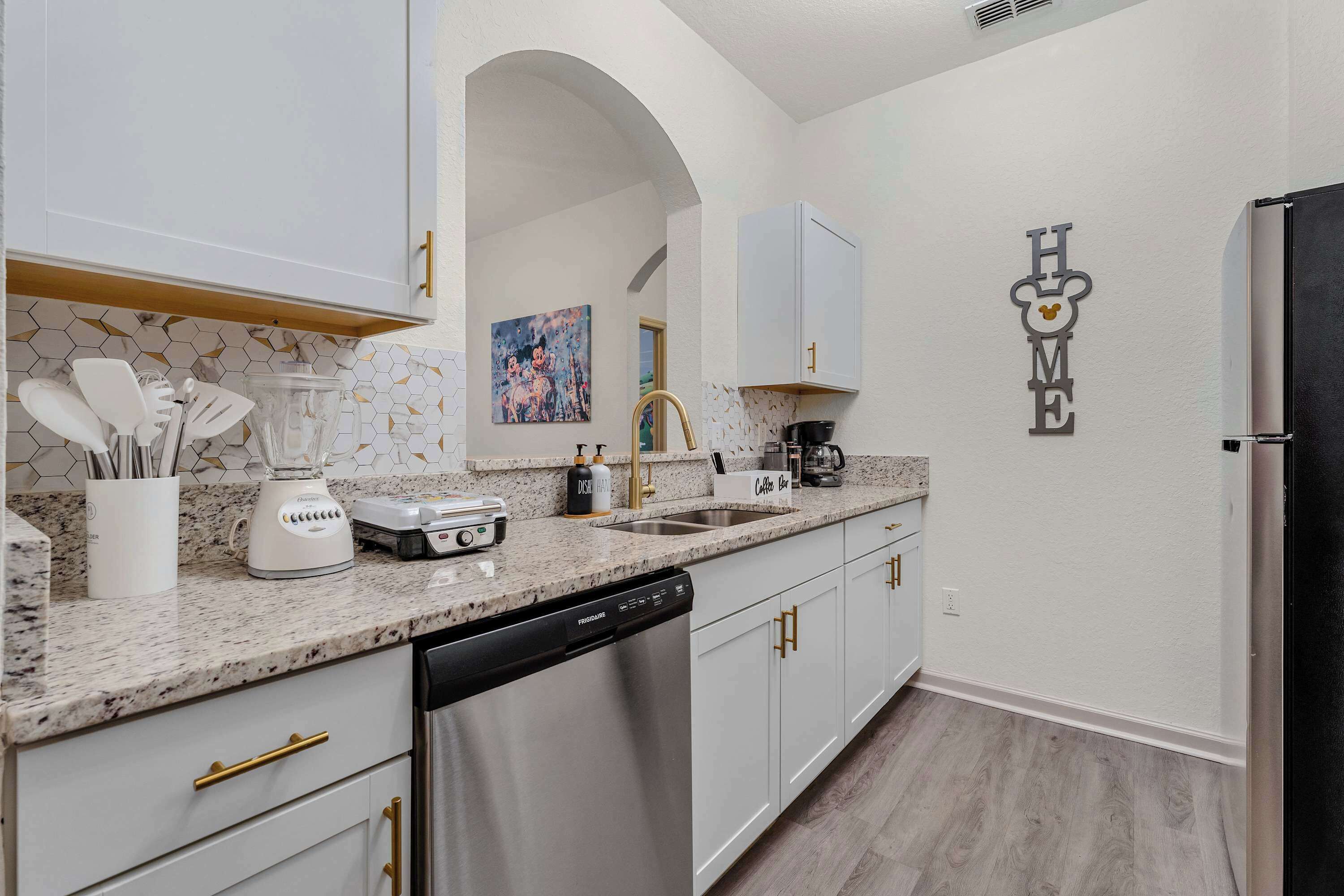 A modern kitchen with white cabinets, a granite countertop, and stainless steel appliances.