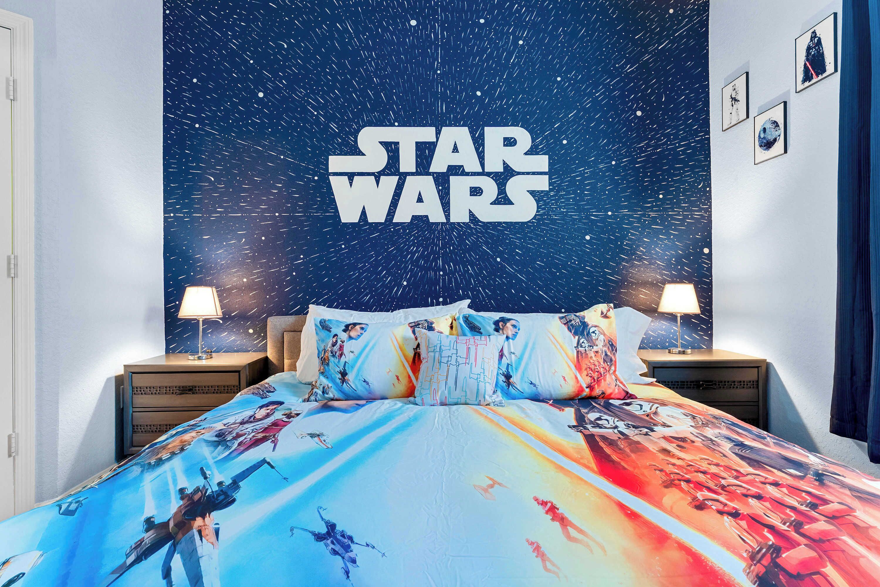 Camera da letto a tema Star Wars con un letto, cuscini e un affresco sulla parete.