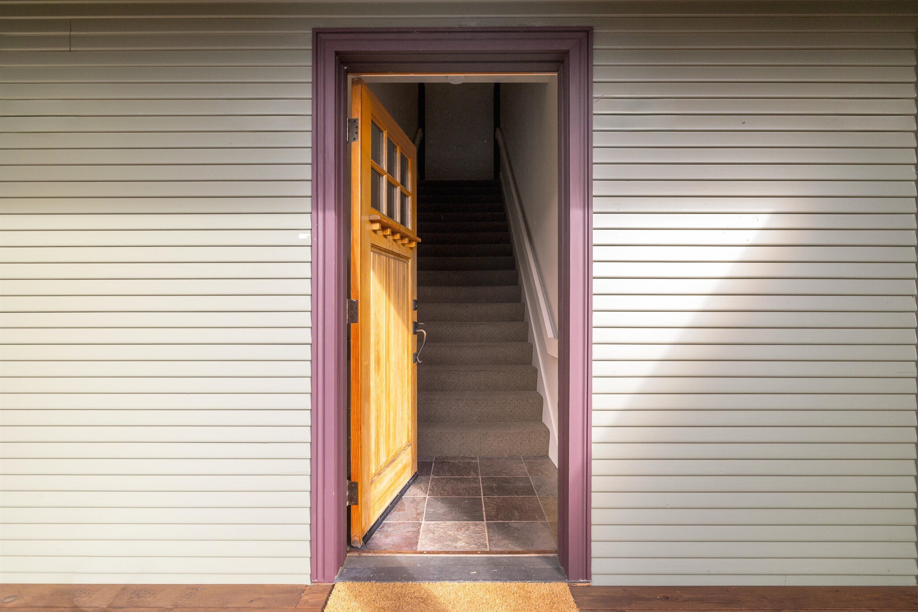 A hallway with a wooden door leading to a staircase.