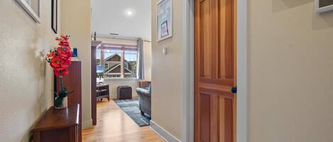 A hallway with wooden flooring, a wooden door, and a small table with a vase of flowers.