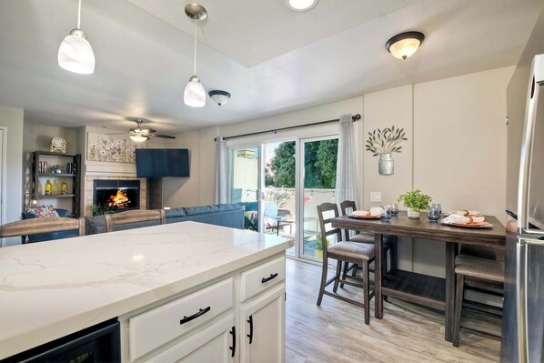 A modern kitchen with a large island, dining area, and a fireplace. - Silver Surf Getaway (Oceanside)