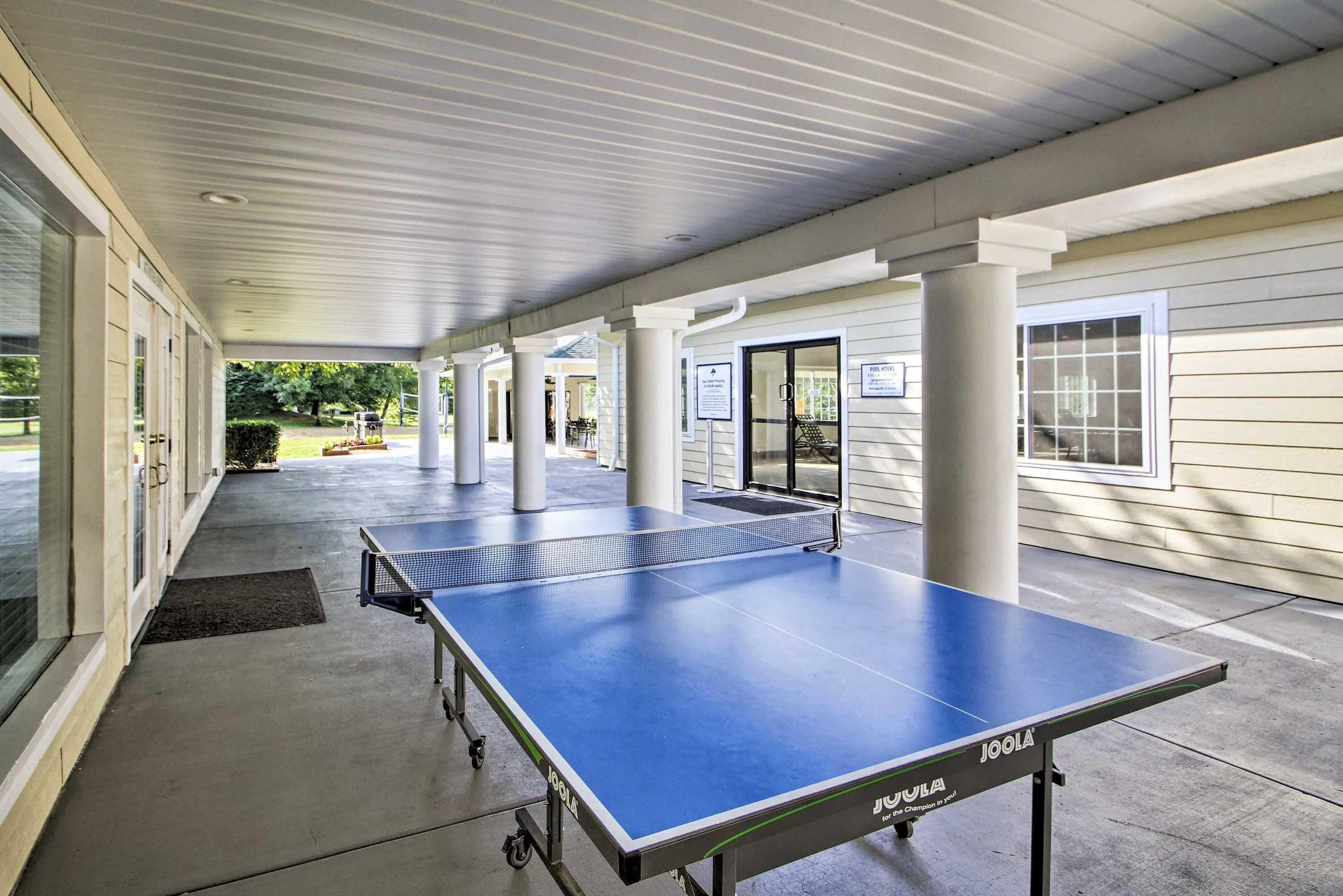 Ein Outdoor-Tischtennis-Tisch der Marke Joola steht auf einem Betonboden unter einem überdachten Bereich.