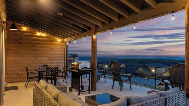 A covered outdoor seating area with wicker furniture, a grill, and a view of a house in the background. - Two Pines Endless Views and Attractions! (Branson)