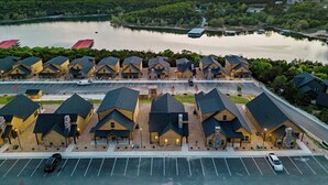 A row of log cabin-style buildings with a parking lot in front, overlooking a lake. - Two Pines Endless Views and Attractions! (Branson)