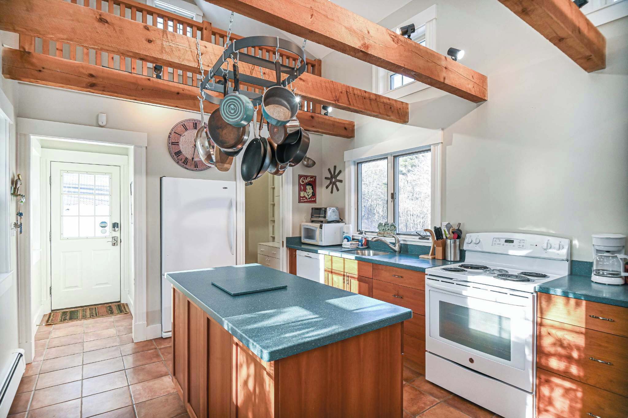 Una cocina con vigas de madera, una estufa blanca y una isla grande con encimera azul.
