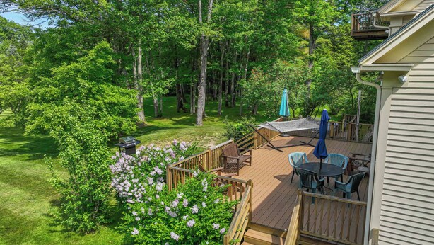 Une terrasse dotée de mobilier d’extérieur, entourée d’une végétation luxuriante et d’arbres.