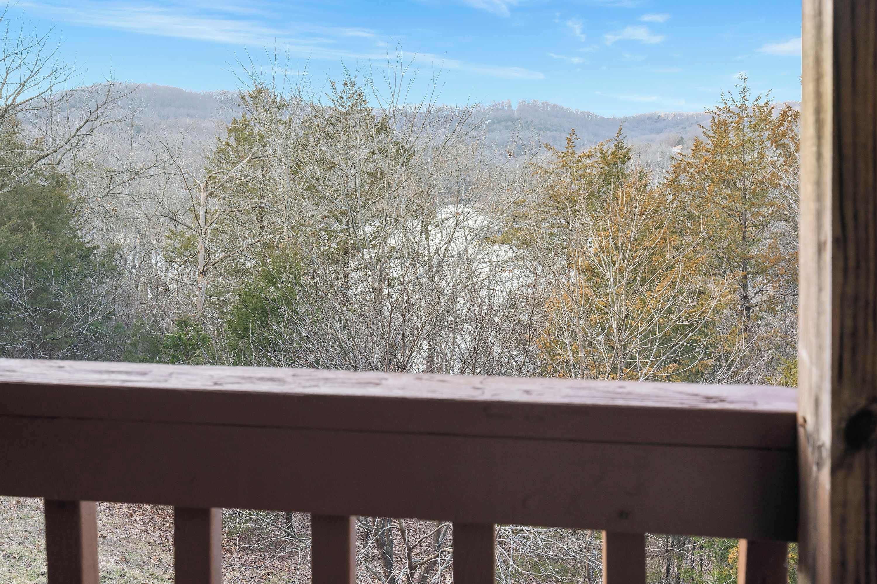 A wooden deck with a view of a forested area and distant hills.